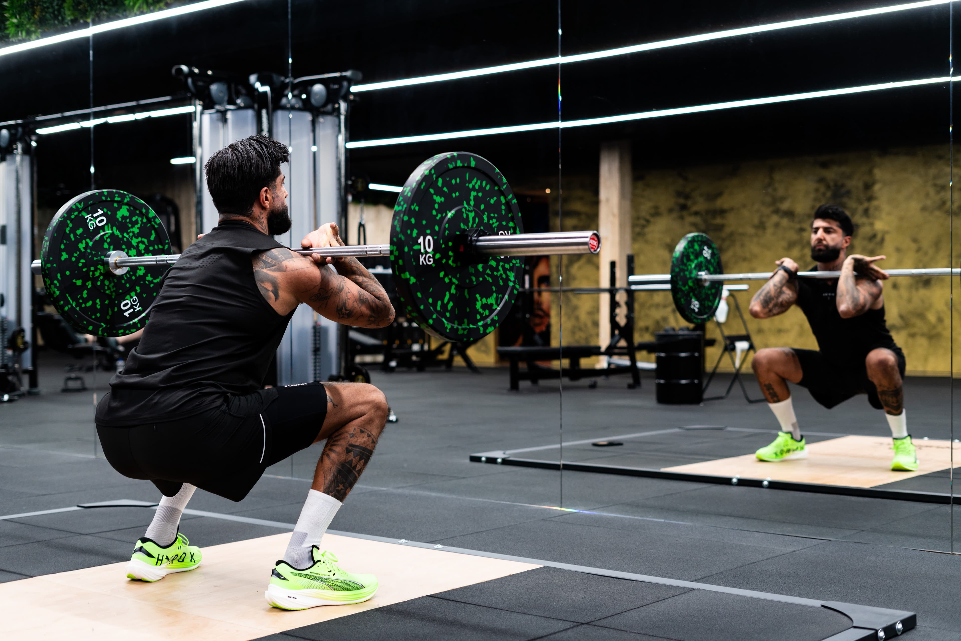 Roman zakt door zijn knieën met een barbell op zijn schouders